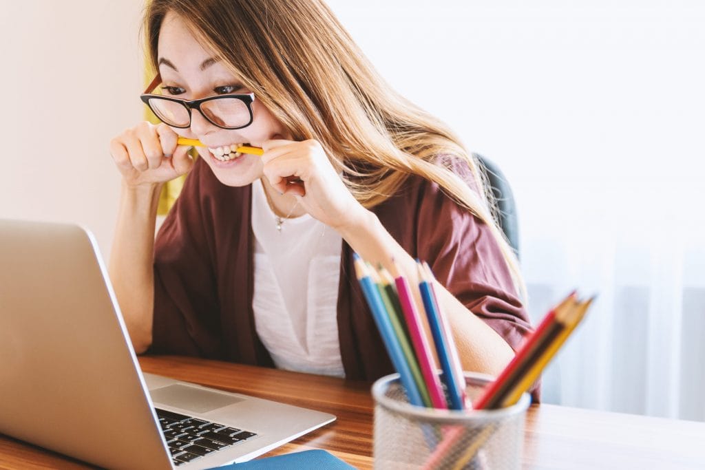 a frustrated manager on her laptop while biting a pencil